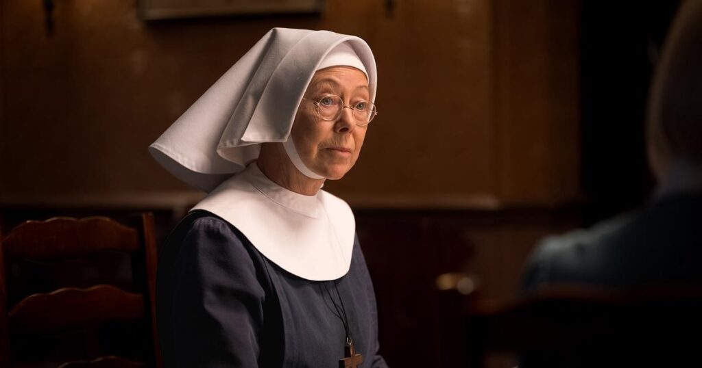 A nun sits on a wooden chair facing another person