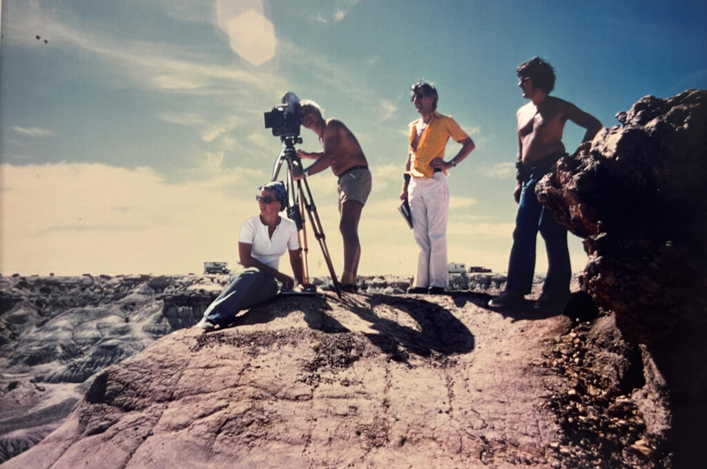 Four people stand atop a canyon cliff with photography gear.