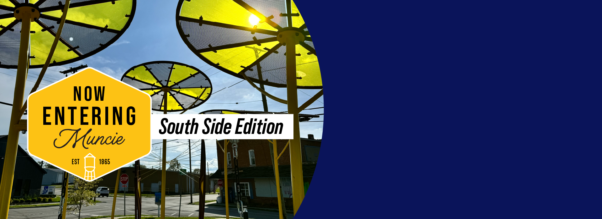 Tall yellow and black umbrella-like structures as public art with the sun shining through and a street with buildings in the background.