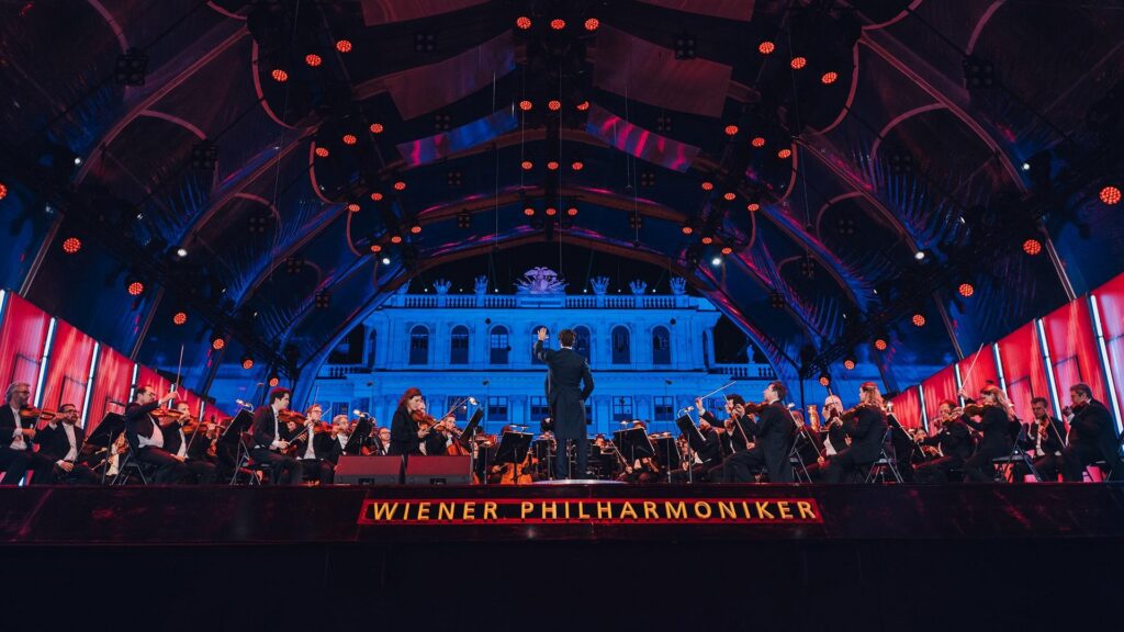 Vienna Philharmonic performs on large, lit up stage.