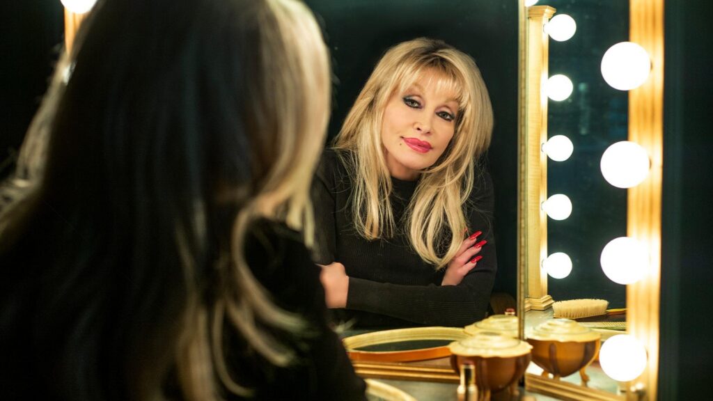 A woman with blond hair looks into a dressing room mirror
