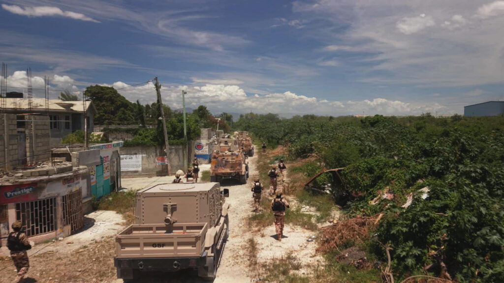 This widest view of the Haitian landscape shows American military marching down dirt roads alongside military trucks.